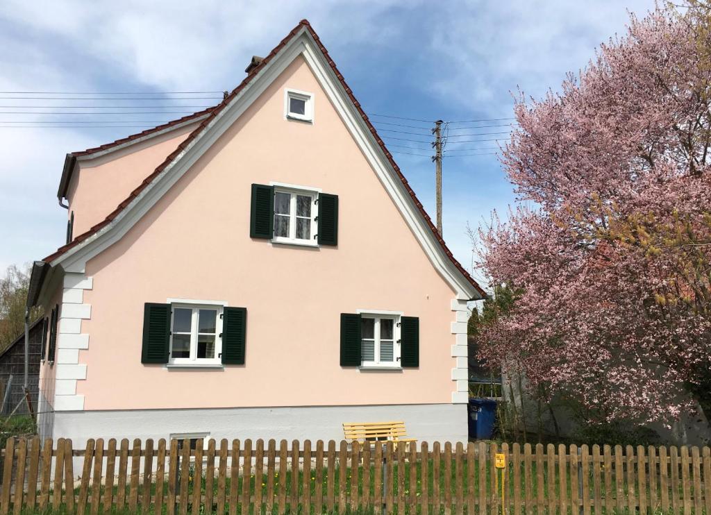 een roze huis met groene luiken en een hek bij Ferienwohnung Kröner in Donauwörth