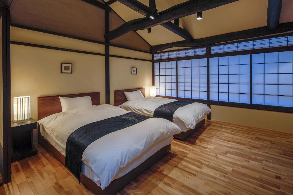a bedroom with two beds and large windows at Obama Machiya Stay in Obama