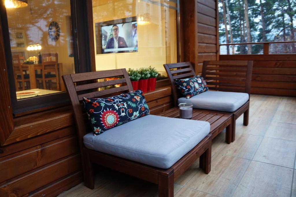 two benches sitting on a porch with pillows at Апартамент "Forest view" в комплекс "Вели Хилс" in Velingrad