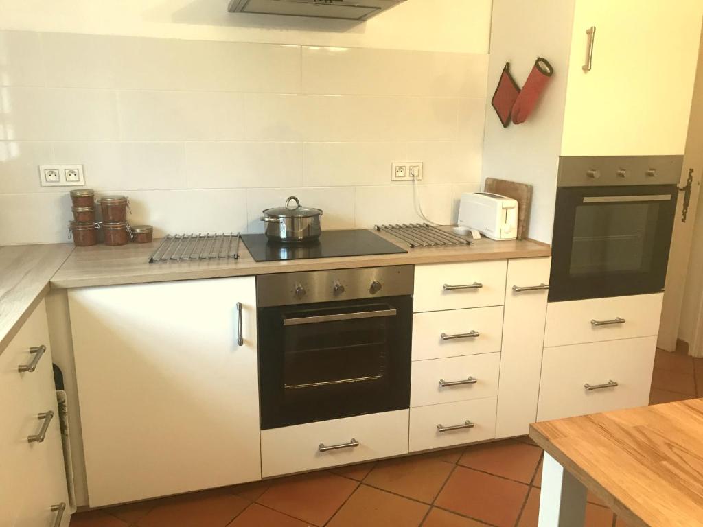 a kitchen with white cabinets and a stove top oven at Les Lauriers in Limoux