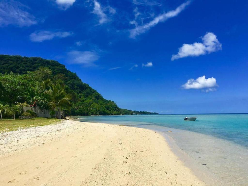 a sandy beach with a boat in the water at Paradise Point Escape in Port Vila