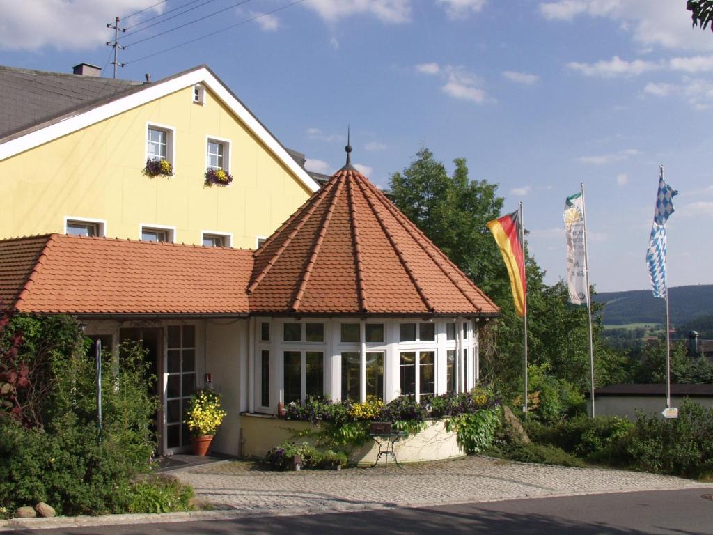 uma casa amarela com telhado de azulejo em WAGNERS Hotel Schönblick, C&C Hotels und Vertrieb GmbH em Fichtelberg