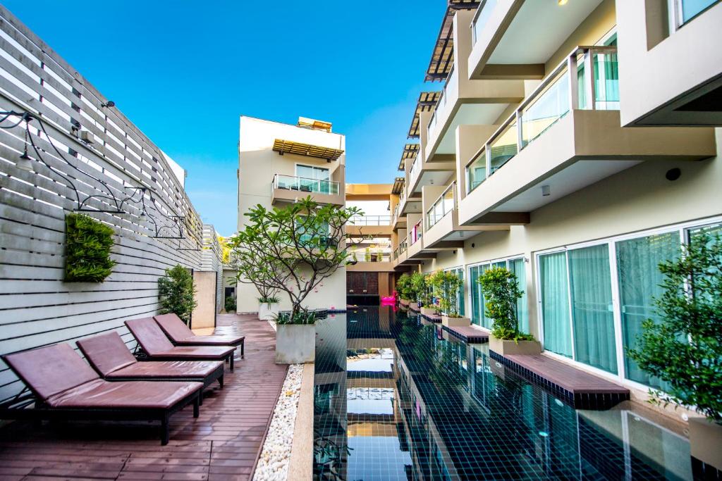 an apartment patio with benches and a swimming pool at Navinda Krabi - SHA Plus in Ao Nang Beach