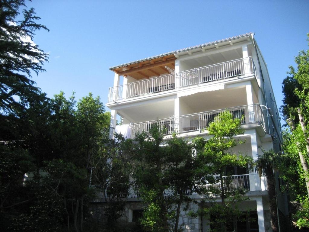 a white apartment building with balconies and trees at Apartments Sonne in Crikvenica