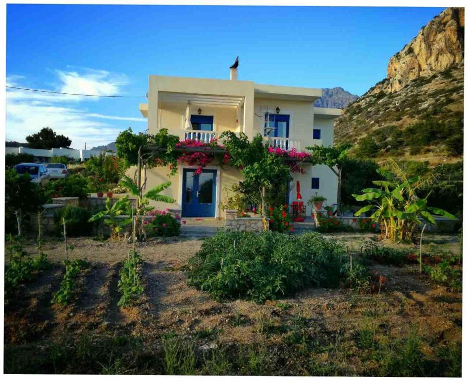 una casa bianca con una porta blu su una montagna di Venetia's Garden a Lefkos Karpathou