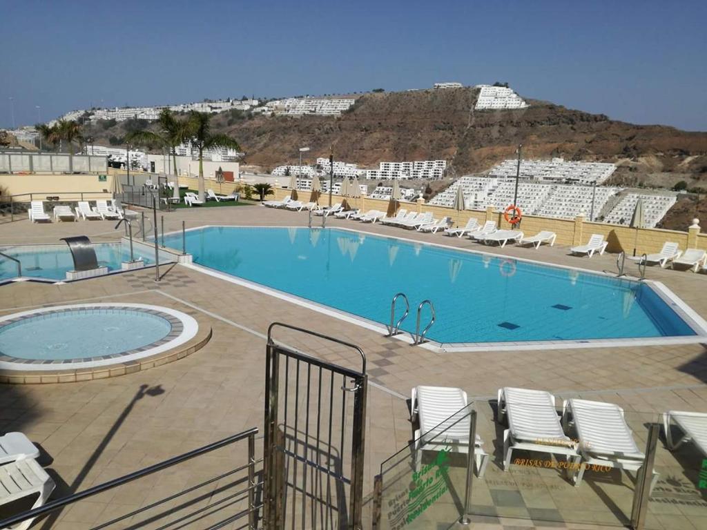 a large swimming pool with lounge chairs at THE 69 in Puerto Rico de Gran Canaria