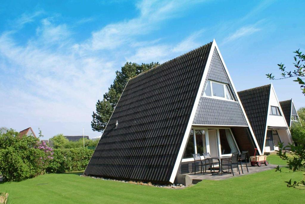 een huis met een metalen dak op een groen gazon bij Zeltdachhaus mit W_LAN in Strandna in Damp