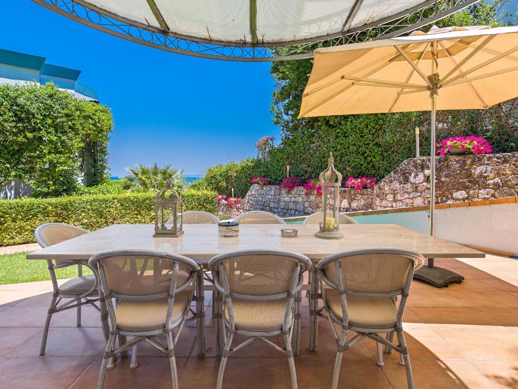 a table with chairs and an umbrella on a patio at Aegean Residence #A - F & B Summer Collection in Kallithea Halkidikis