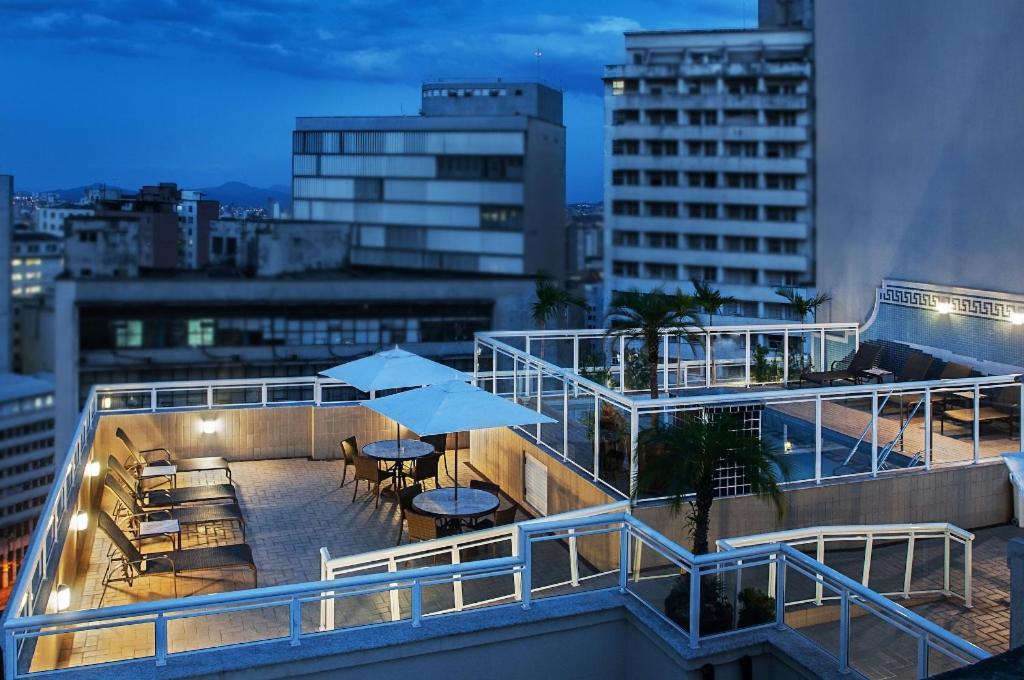 un balcón con mesas y sombrillas en un edificio en Normandy Hotel, en Belo Horizonte