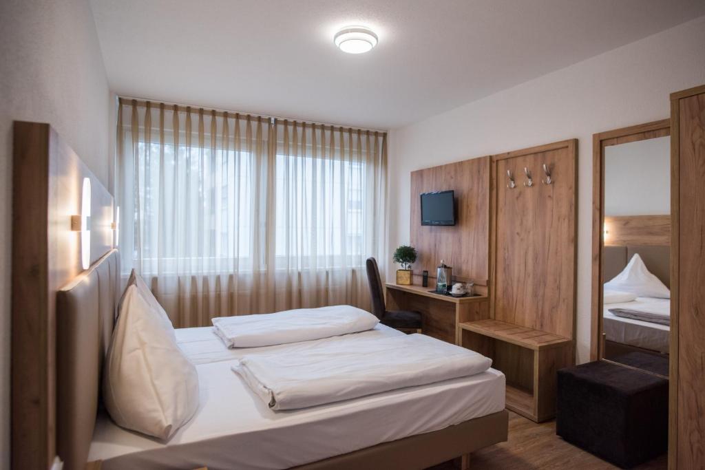 a hotel room with two beds and a mirror at Hotel Leo in Eggenstein-Leopoldshafen