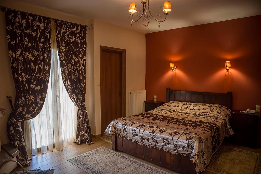 a bedroom with a bed and a large window at Andromeda Hotel Limni Plastira in Koutsodímos