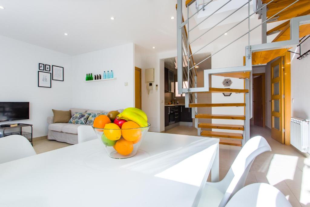 a white living room with a bowl of fruit on a table at Feriapiso Apartments Palmer in Hospitalet de Llobregat