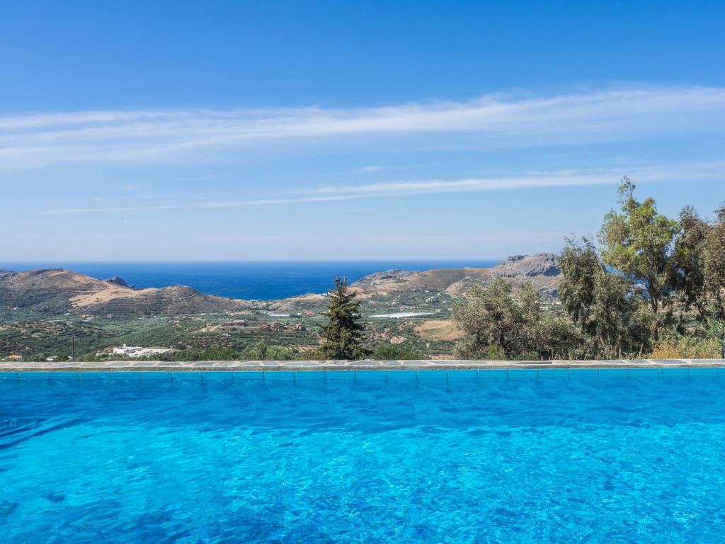 una piscina de agua azul y montañas de fondo en Villa Mariou en Plakiás