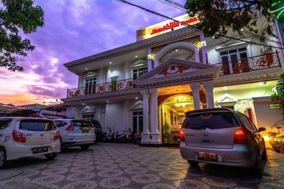 een gebouw waar auto's voor geparkeerd staan bij Hotel Alifa Syariah in Padang