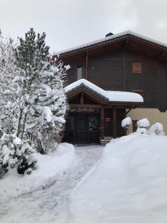 a building covered in snow with a tree in front of it at L'appartement des ours in Les Houches