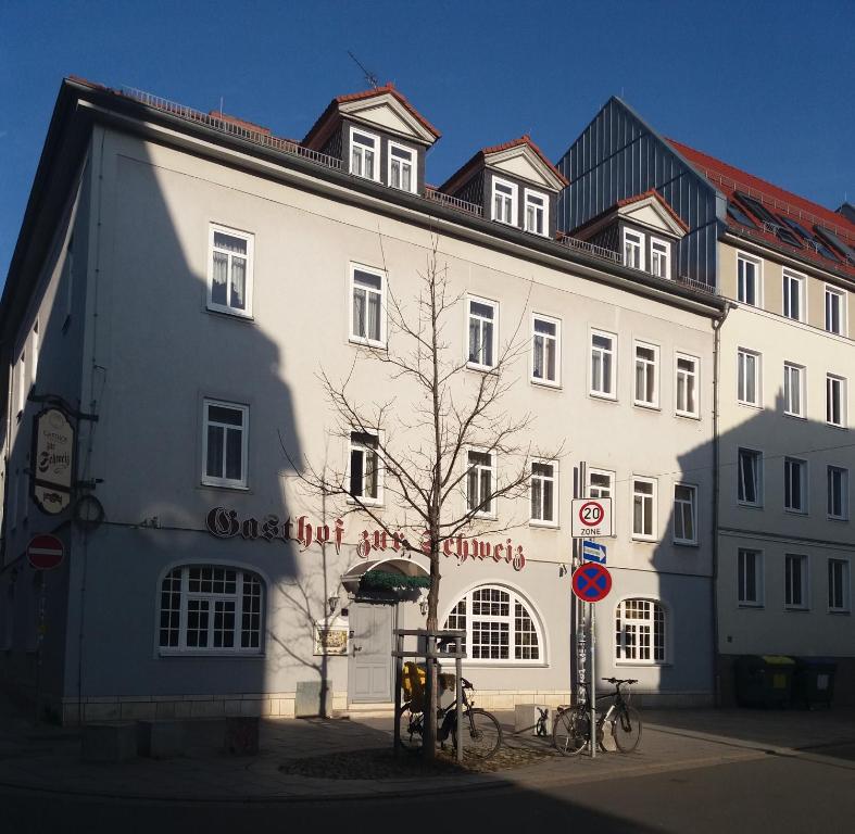 un grand bâtiment blanc avec des vélos garés devant. dans l'établissement Gasthof zur Schweiz, à Iéna