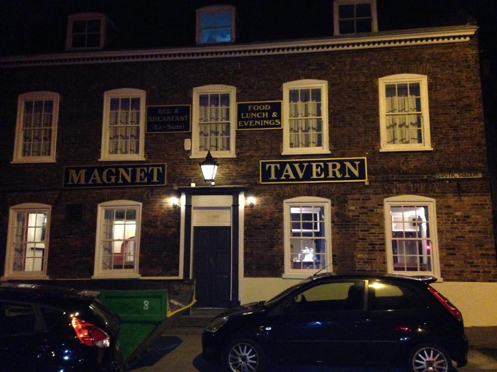 un'auto parcheggiata di fronte a un edificio di mattoni di notte di The Magnet Tavern a Boston