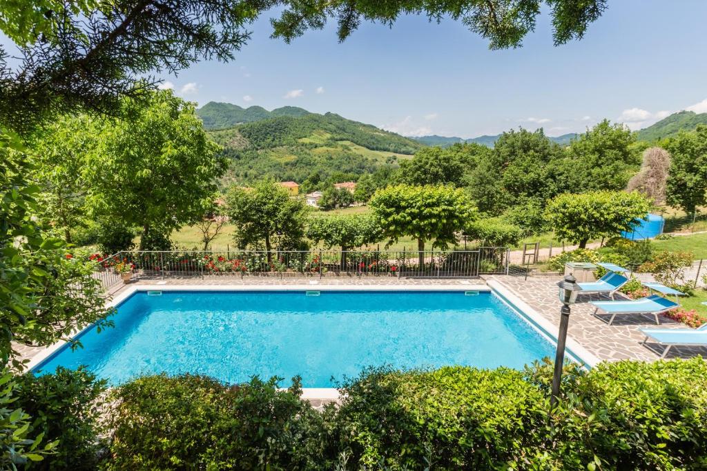 una piscina con sillas, árboles y montañas en el fondo en Villa degli Artisti, en Piobbico