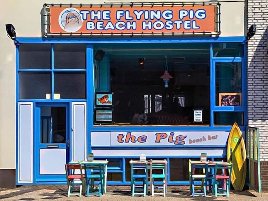 ノールトウェイク・アーン・ゼーにあるThe Flying Pig Beach Hostel, ages 18 - 40のビーチハウスの前に椅子とテーブルがあります。