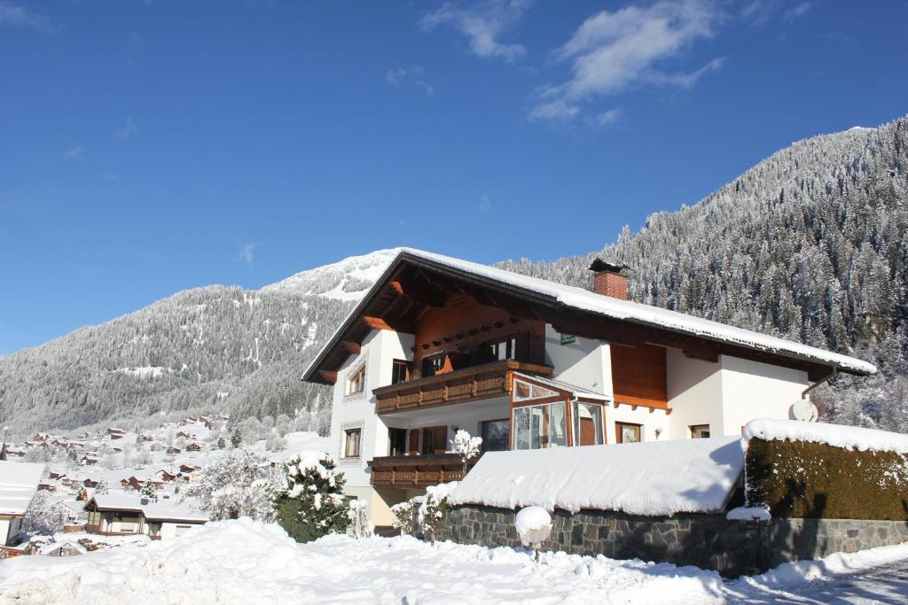ein schneebedecktes Haus mit Bergen im Hintergrund in der Unterkunft Haus Netzer Irma in Sankt Gallenkirch