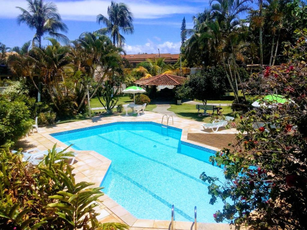 a swimming pool in a yard with palm trees at Pousada Chez Moi in Cabo Frio