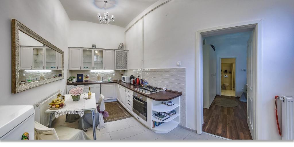 ブダペストにあるJulia's Homeの白いキャビネットとテーブル付きのキッチンが備わります。