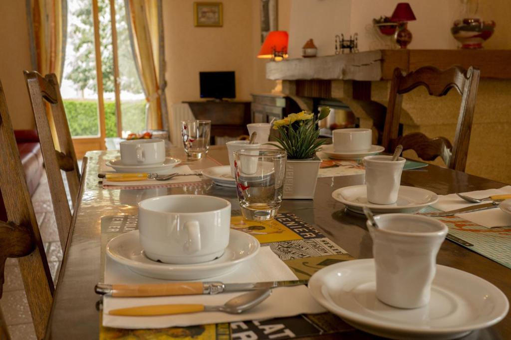 a table with white cups and saucers on it at Les Louchardes in La Rochepot