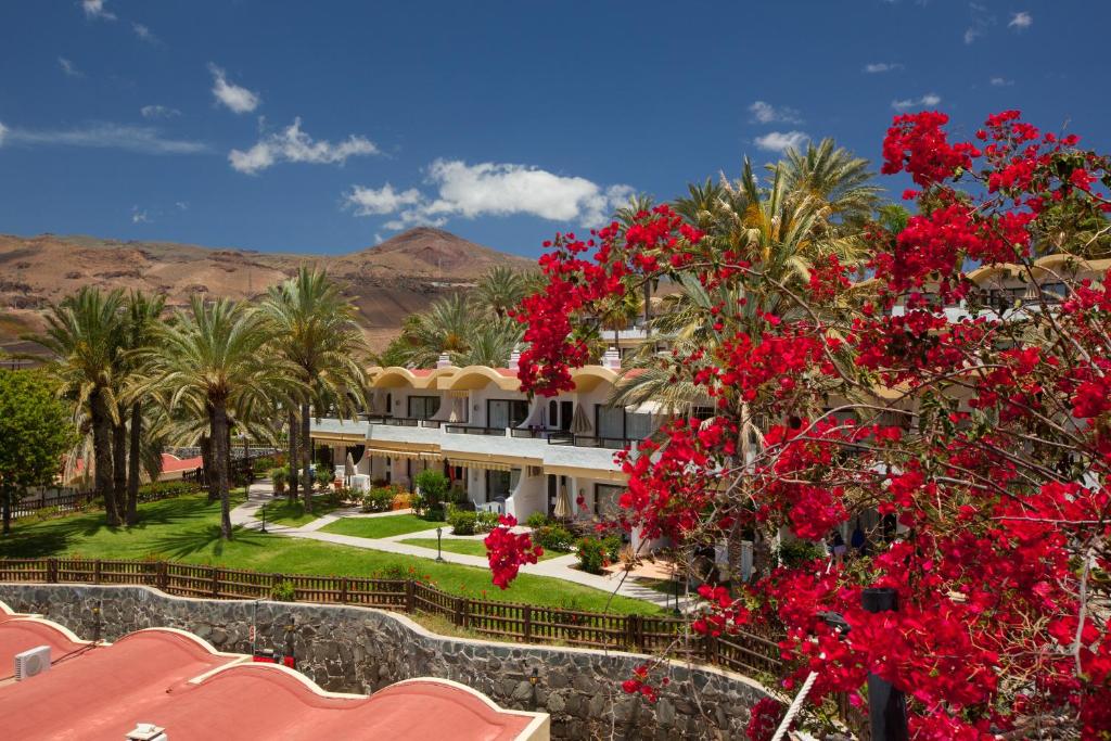 duży dom z czerwonymi kwiatami przed nim w obiekcie Grupotel Las Pitas w mieście San Agustin