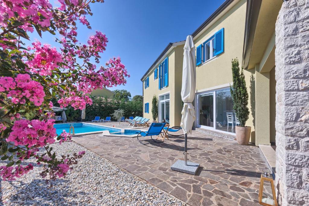 a patio with a pool and an umbrella and flowers at Villa 1519 in Žminj