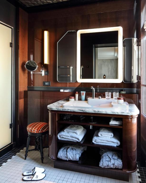 a bathroom with a sink and a mirror and a stool at Hotel Les Bains Paris in Paris
