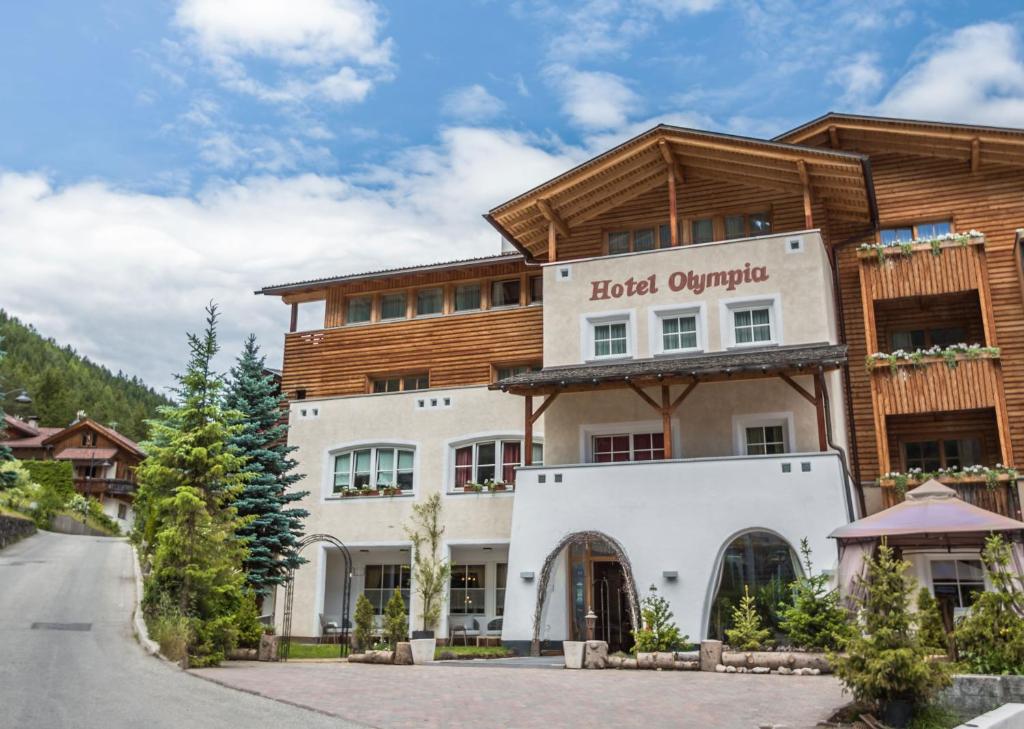 a hotel surrounded by trees and a road at Hotel Olympia in San Vigilio Di Marebbe