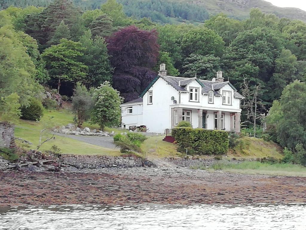 a white house on the shore of a body of water at Lochwood Guest House in Lochgoilhead