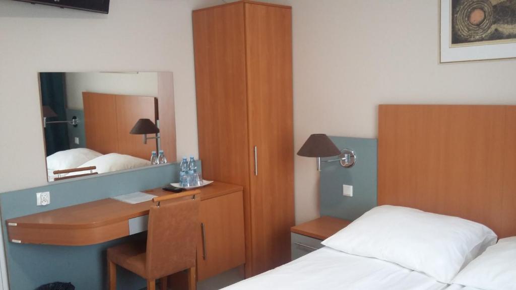 - une chambre avec un bureau, un lit et un miroir dans l'établissement Noclegi, Restauracja Eden, à Witaszyce