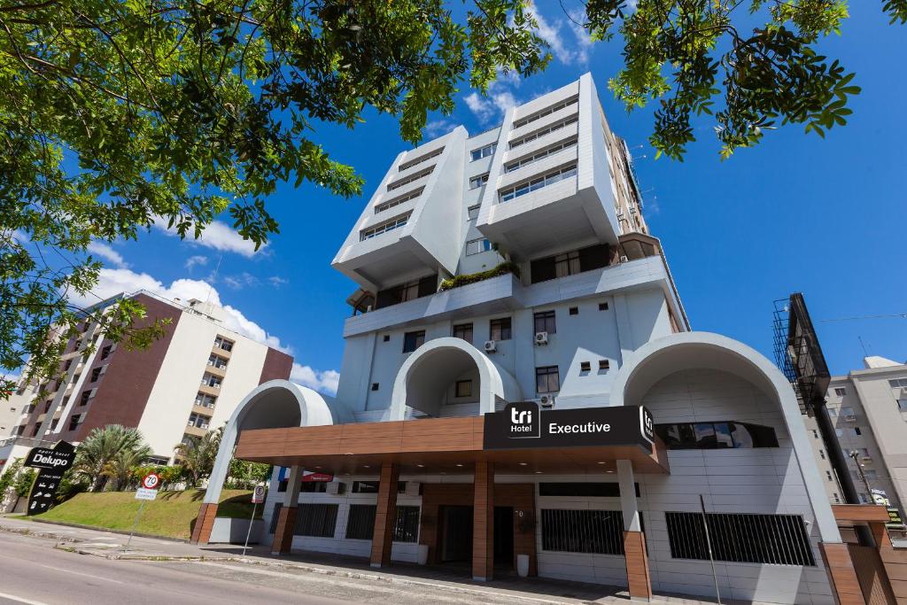 un bâtiment blanc avec un panneau devant lui dans l'établissement Tri Hotel Executive Criciúma, à Criciúma
