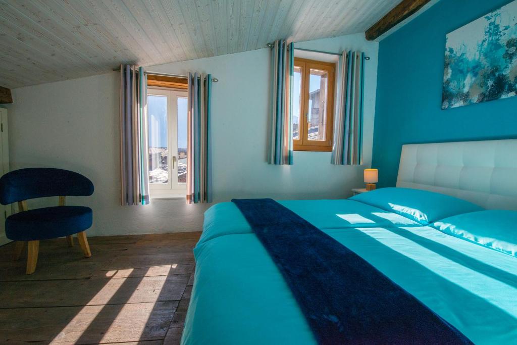 a blue bedroom with a bed and a chair at Chez Constance in Saillon