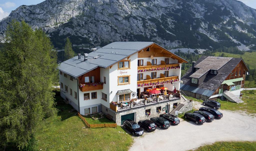 ein großes Gebäude mit davor geparkt in der Unterkunft Hotel Alpenrose in Tauplitzalm