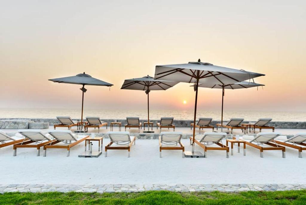 Veranda Residence Pattaya x Sea & Sky View في نا جومتين: مجموعة من الكراسي والمظلات على الشاطئ