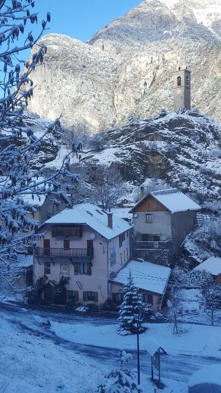 une maison avec de la neige devant une montagne dans l'établissement Gîte Auberge Les Terres Blanches de Méolans, à Méolans