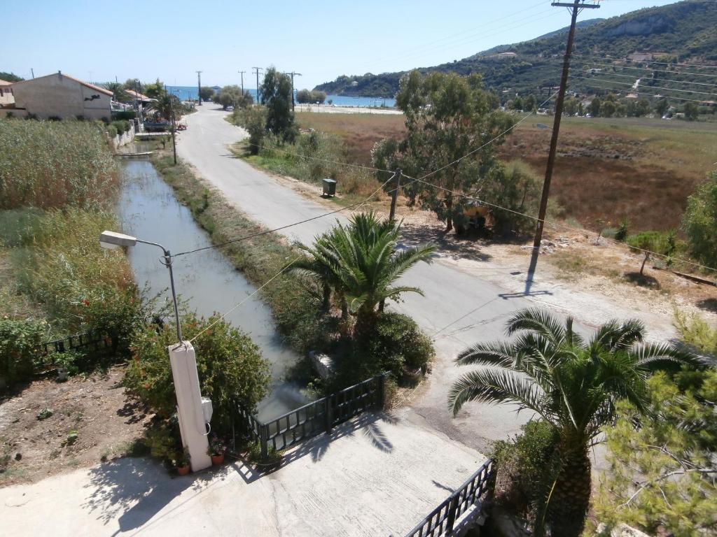 a walkway next to a river with palm trees at Pansion Porto Tsi Ostrias in Keri