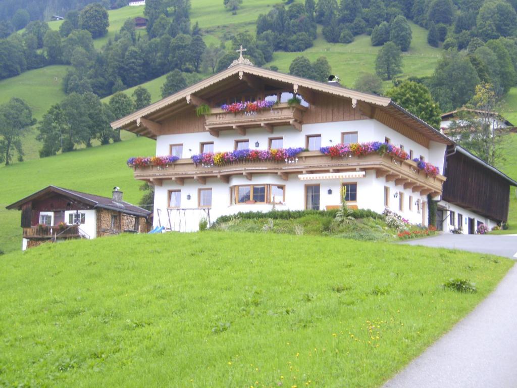 ein Haus auf einem Hügel mit Blumen darauf in der Unterkunft Bauernhof Hundbichl in Brixen im Thale