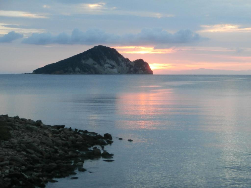 an island in the water with a sunset at Pansion Porto Tsi Ostrias in Keri