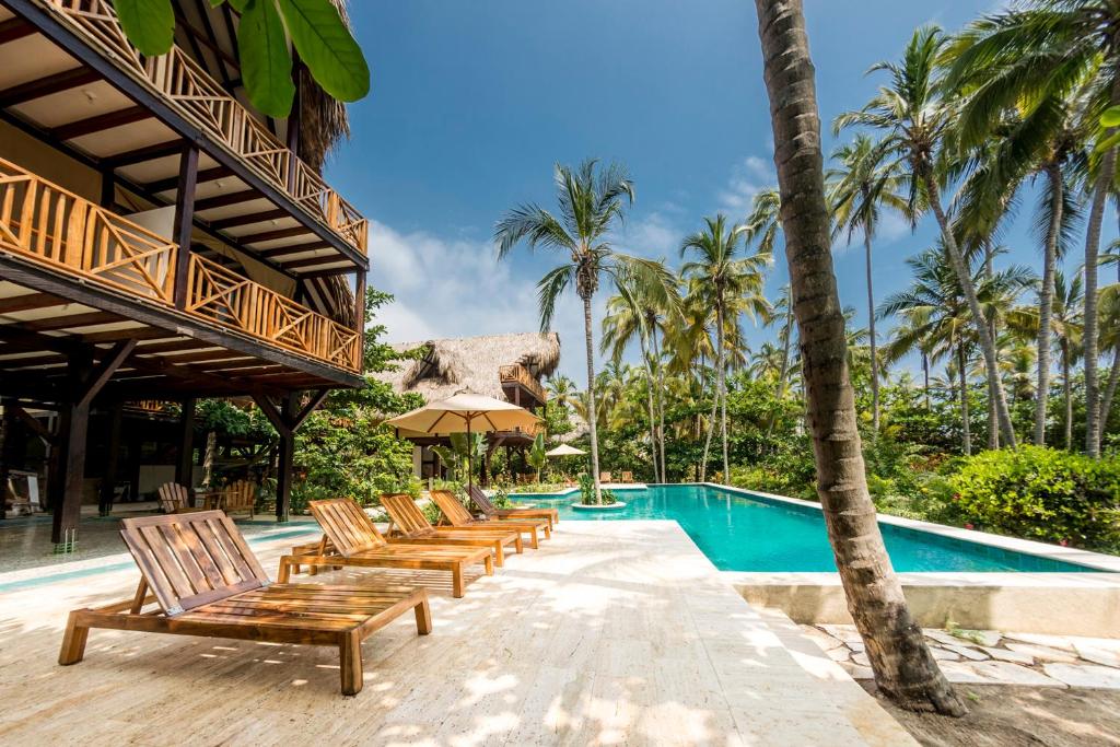 Cayena Beach Villa في Guachaca: صف كراسي للجلوس بجانب مسبح
