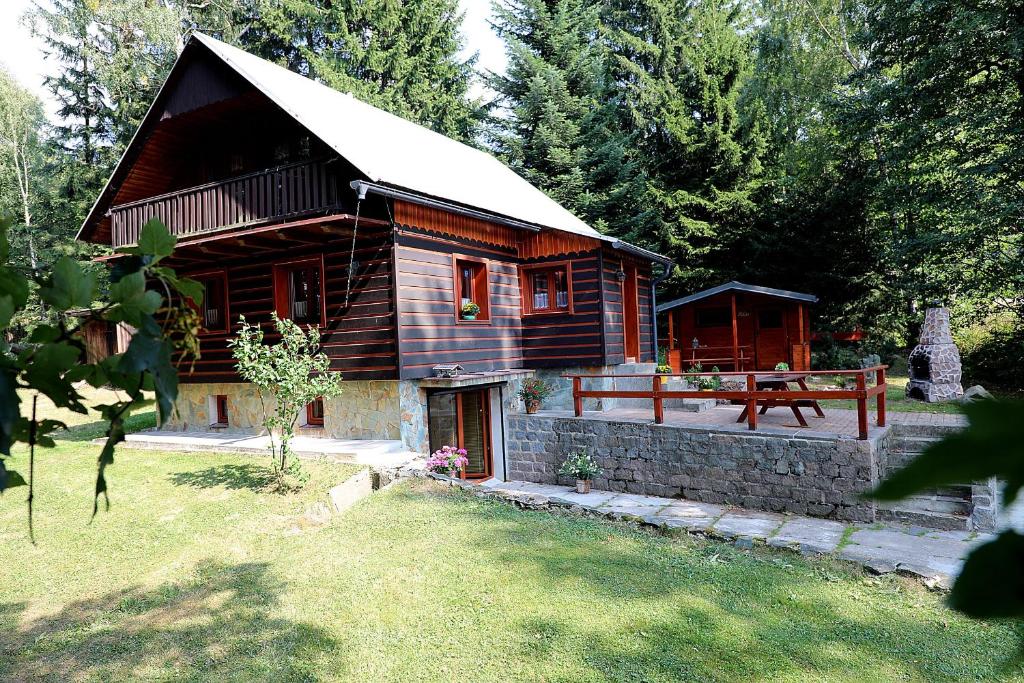 a log cabin with a porch and a bench at Chata U Studánky in Deštné v Orlických horách