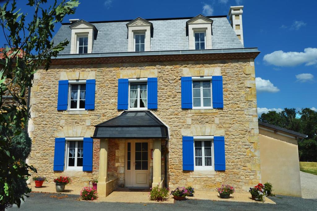 una antigua casa de piedra con persianas azules en Domaine de Chantegros, en Eyzerac