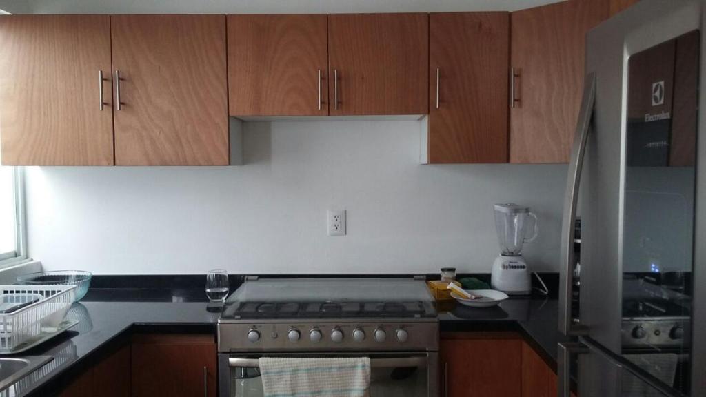 a kitchen with wooden cabinets and a stove top oven at Casa Mariel in San Luis Potosí