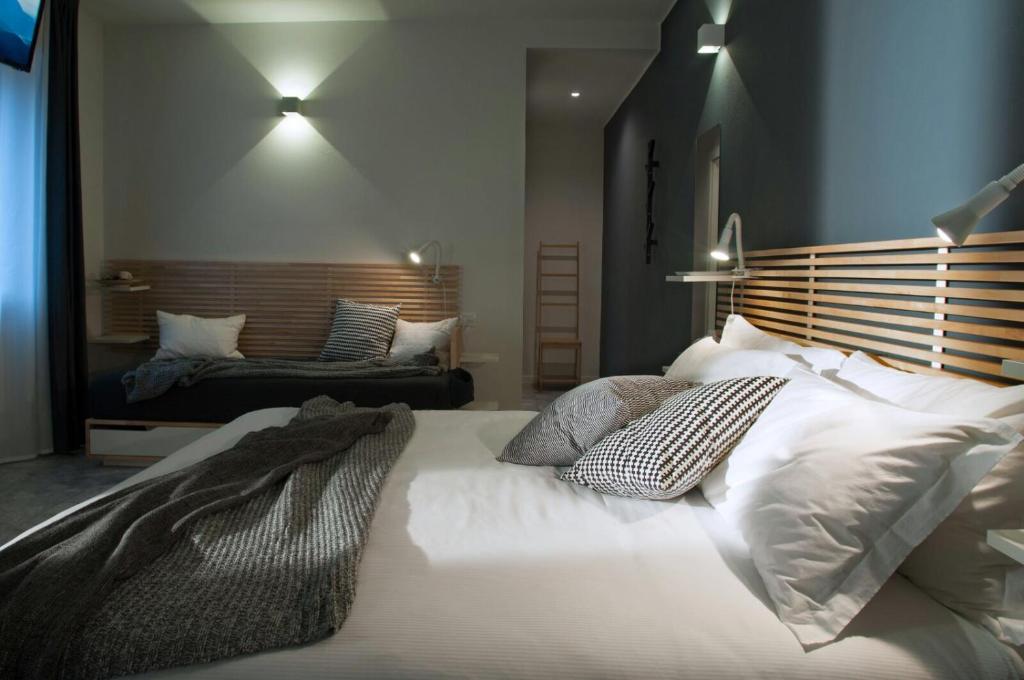 una camera da letto con un grande letto con lenzuola e cuscini bianchi di Relais Merizzi a Tirano