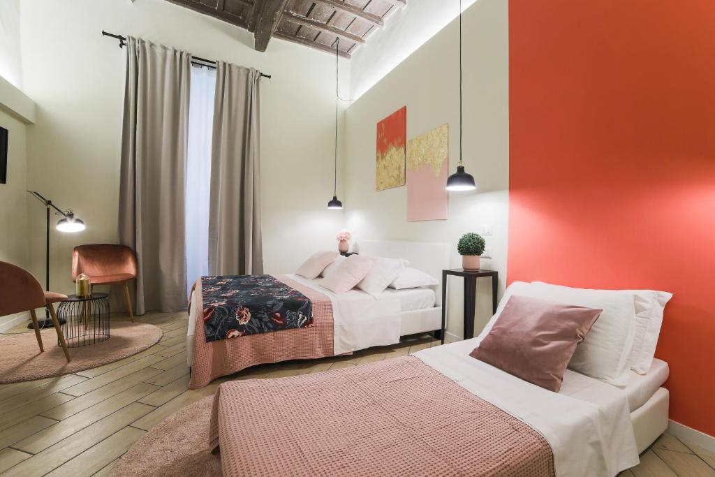 a bedroom with two beds and a red wall at Pantheon Unique Rooms in Rome