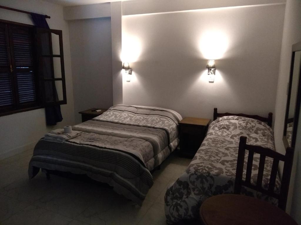 2 łóżka w małym pokoju z oświetleniem na ścianie w obiekcie Amaneceres w mieście Salta