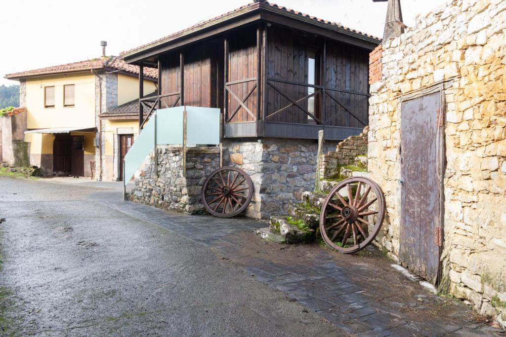 ein altes Gebäude mit zwei abgedeckten Rädern neben einer Straße in der Unterkunft Casa Delfina in Pravia