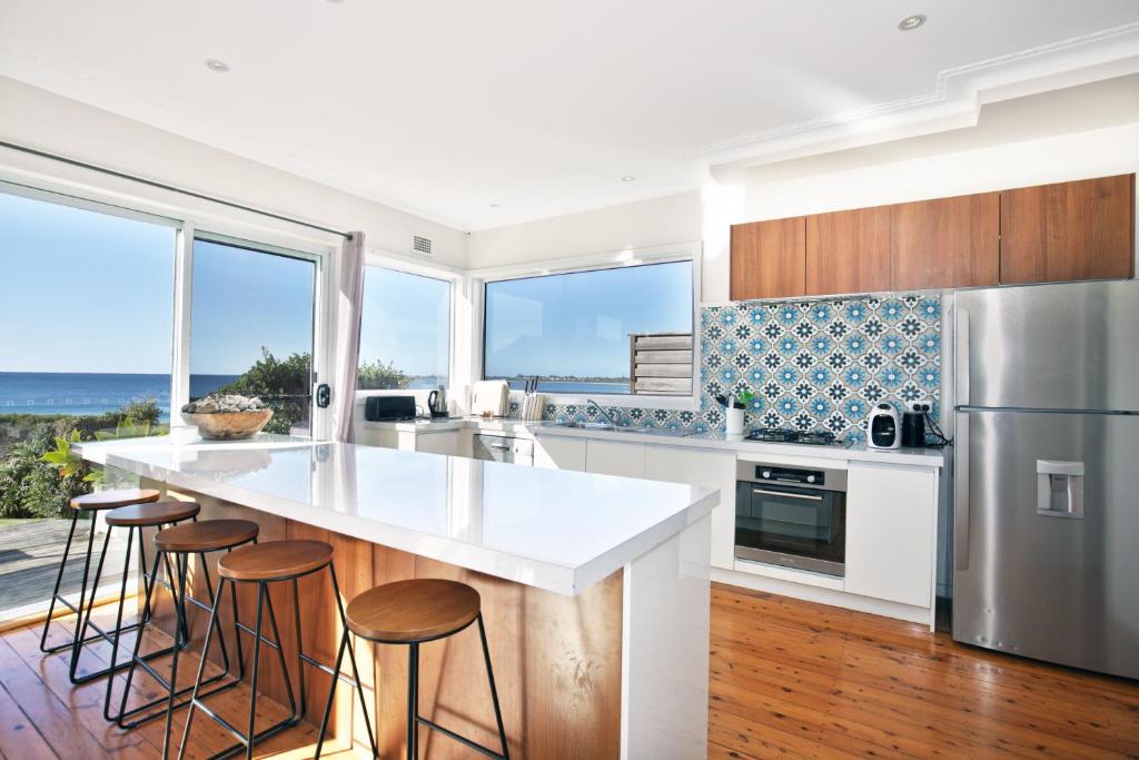 a kitchen with a large white counter and some windows at Culburra Beachhouse in Greenwell Point